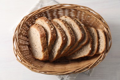 Photo of Slices of fresh homemade bread in wicker basket on white wooden table, top view