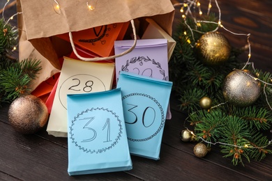 Photo of Colorful paper bags and Christmas decor on wooden table, closeup. New Year advent calendar