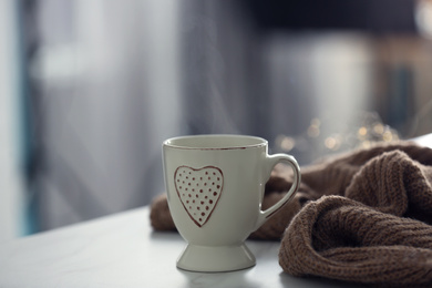 Photo of Delicious morning coffee and knitted sweater on white table indoors
