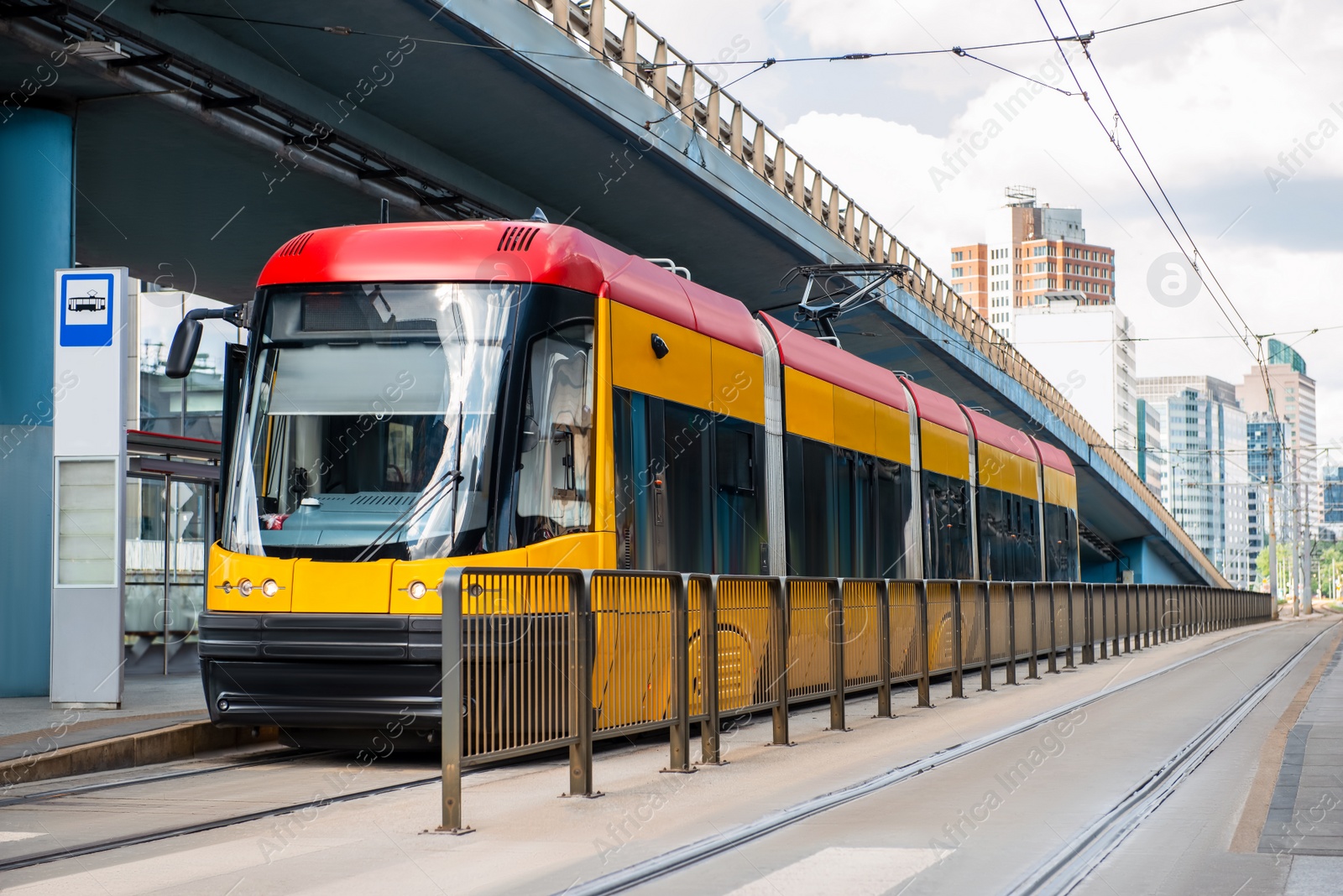 Photo of Modern streetcar near tram stop on sunny day. Public transport