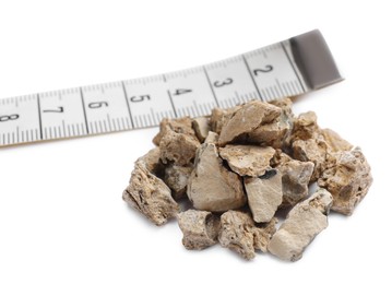 Photo of Pile of kidney stones and measuring tape on white background