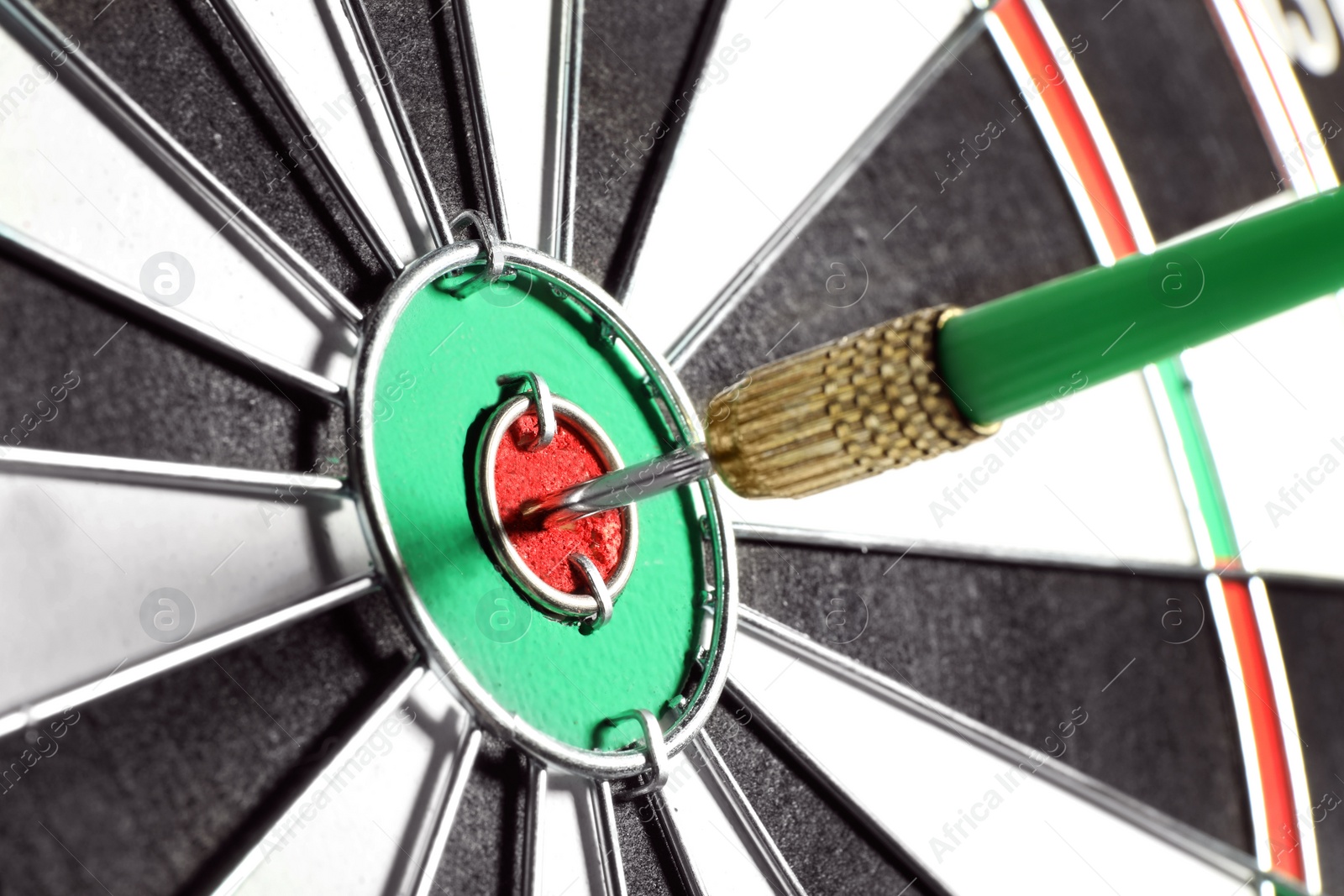 Photo of Dart board with green arrow hitting target, closeup