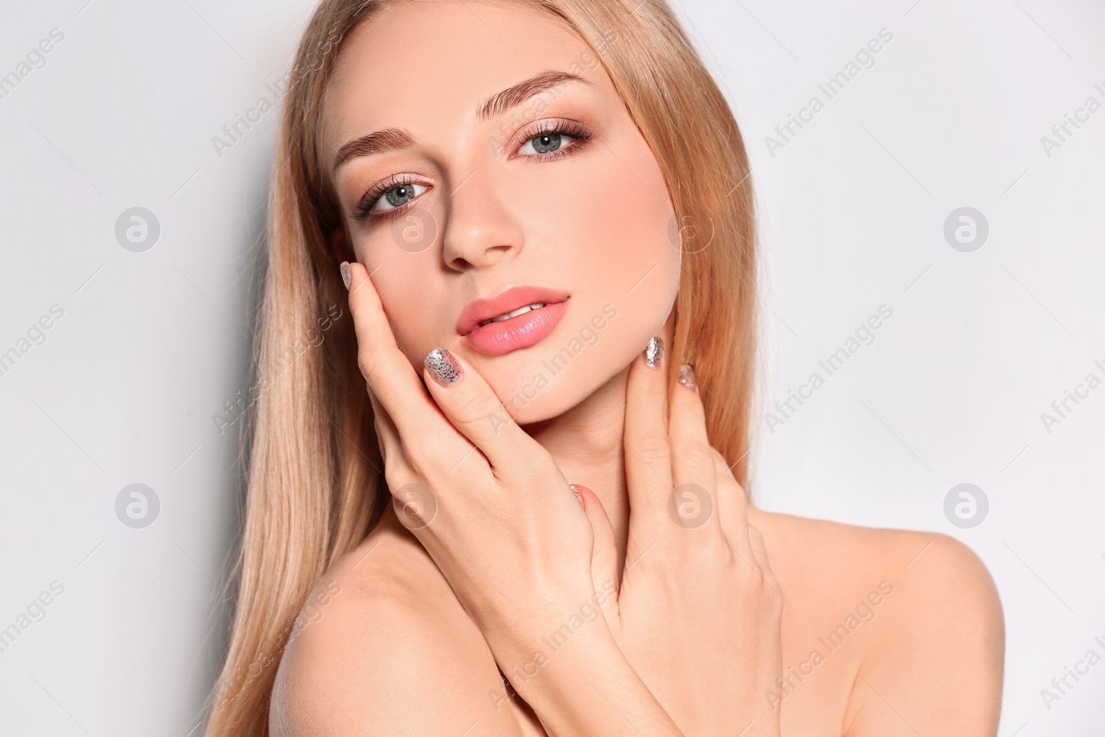 Photo of Beautiful young woman with shiny manicure on light background, closeup. Nail polish trends