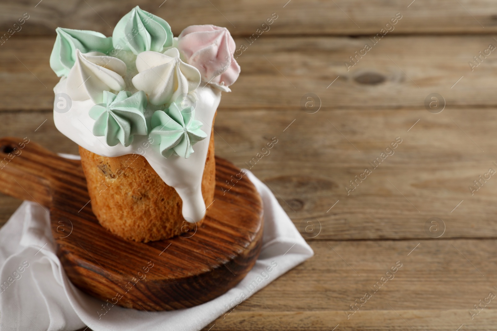 Photo of Traditional Easter cake decorated with meringues on wooden table, space for text