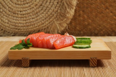 Photo of Delicious sashimi set of salmon and shrimps served with cucumbers and parsley on bamboo mat