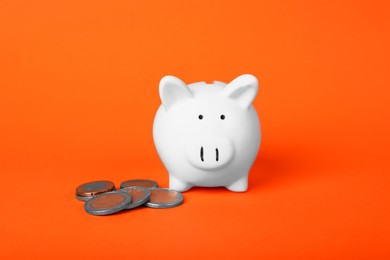 Photo of Ceramic piggy bank and coins on orange background. Financial savings