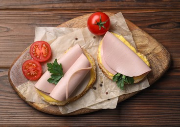Photo of Delicious sandwiches with boiled sausage, cheese and tomatoes on wooden table, top view