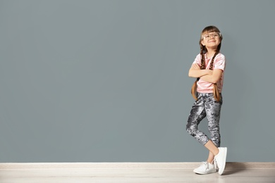 Portrait of cute little girl near gray wall