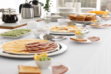 Photo of Clean dishware and different meals for breakfast on white table indoors. Buffet service