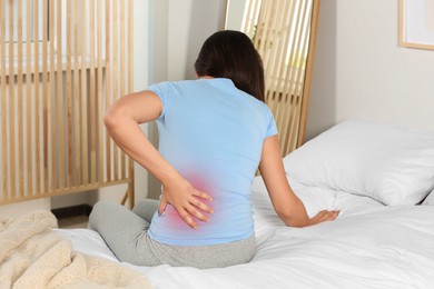 Image of Woman suffering from back pain on bed at home