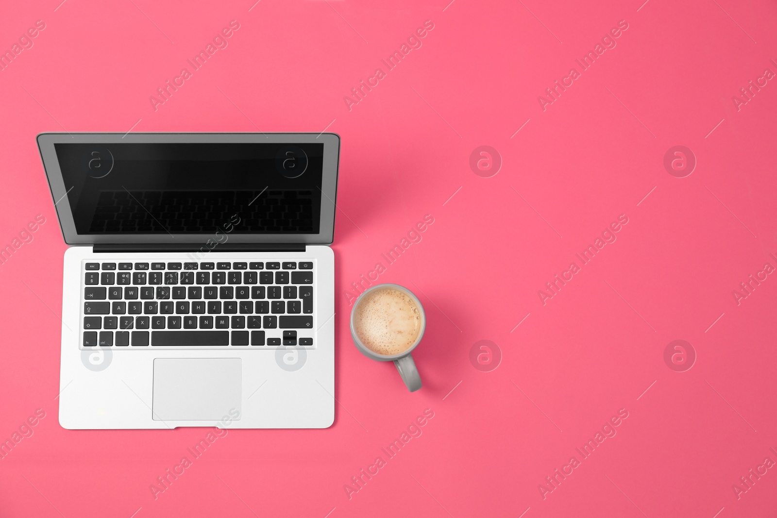 Photo of Modern laptop and cup of coffee on pink background, top view. Space for text