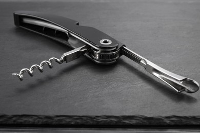 Photo of One corkscrew (sommelier knife) on grey table, closeup