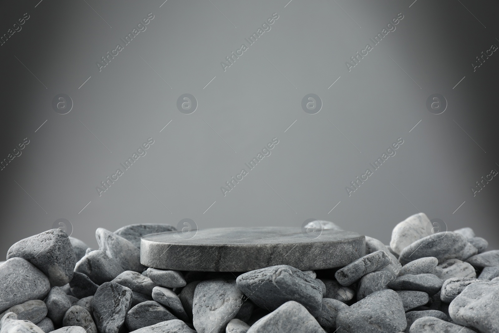 Photo of Presentation for product. Stone and pebbles on grey background. Space for text