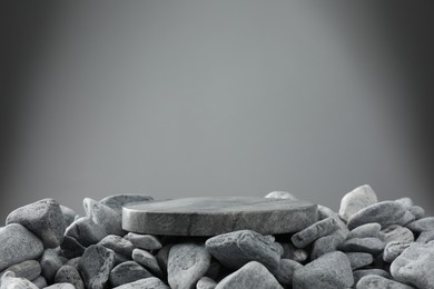 Photo of Presentation for product. Stone and pebbles on grey background. Space for text