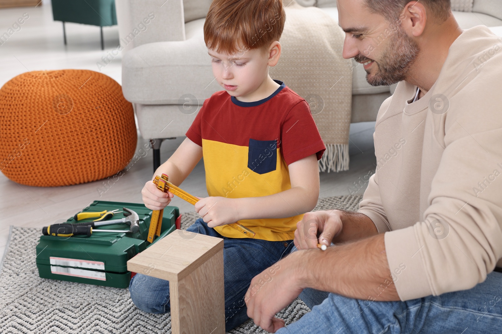 Photo of Father and son measuring shelf together at home. Repair work