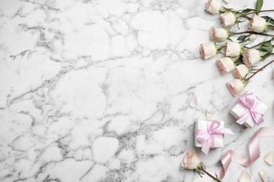 Photo of Flat lay composition with beautiful roses and gift boxes on marble background. Space for text