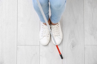 Photo of Blind person with long cane standing indoors, top view