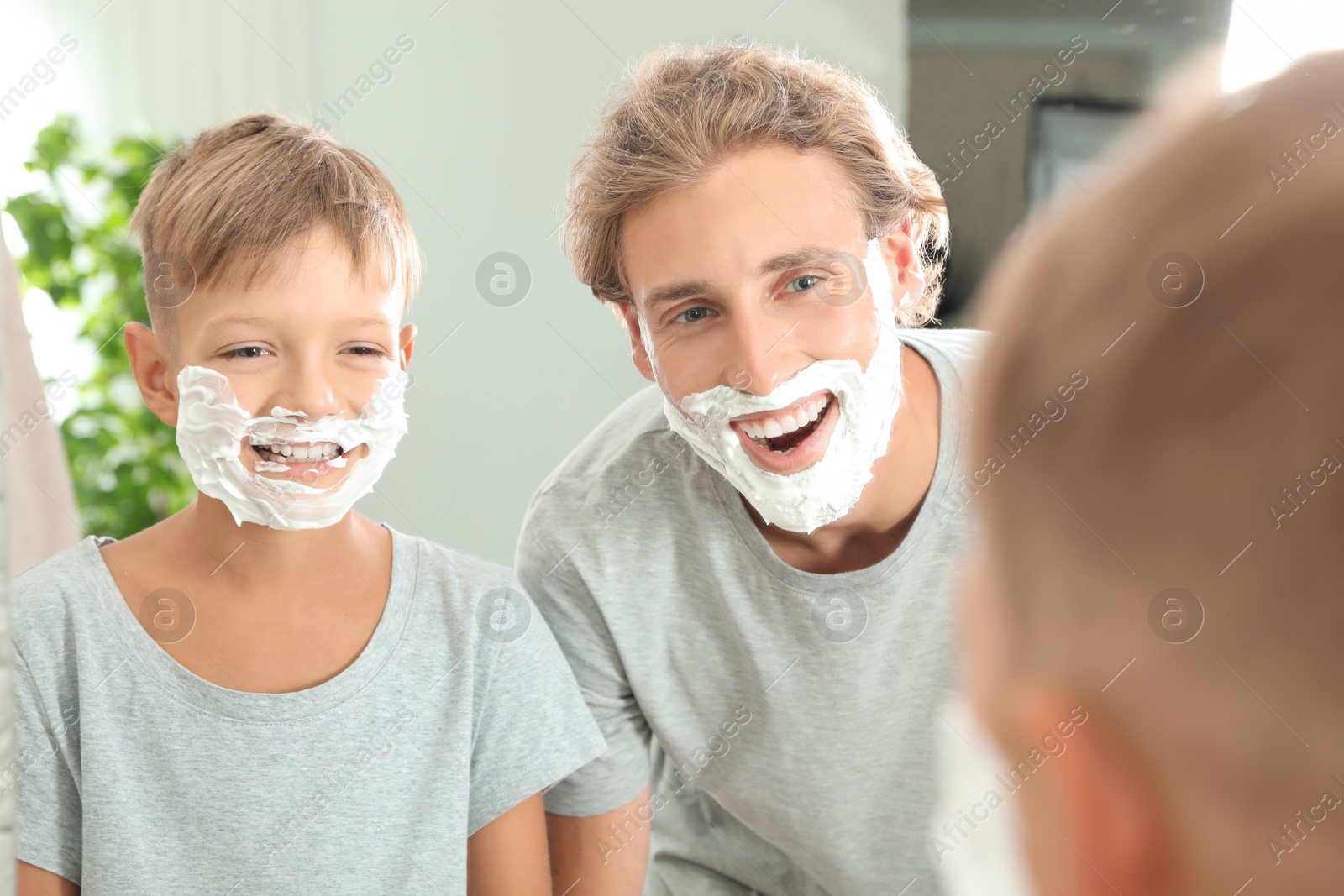 Photo of Father and son with shaving foam on faces in bathroom