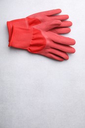 Photo of Pair of red gardening gloves on light grey table, above view. Space for text