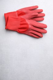 Pair of red gardening gloves on light grey table, above view. Space for text