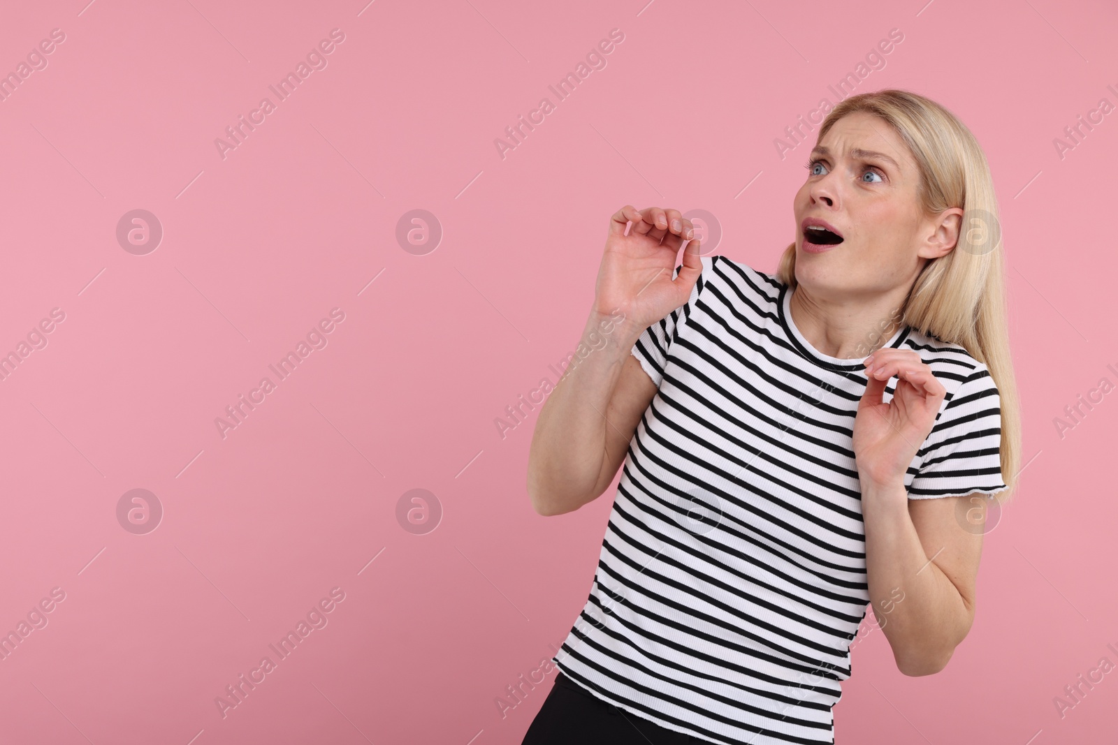 Photo of Portrait of surprised woman on pink background, space for text