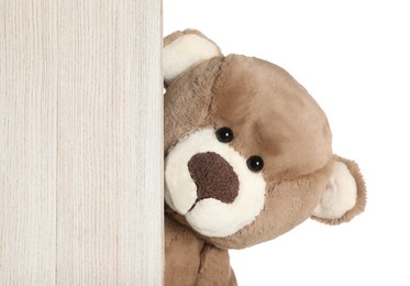 Photo of Cute teddy bear peeking out of wooden board on white background