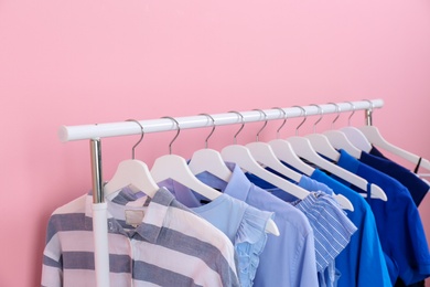 Photo of Rack with bright clothes on color background