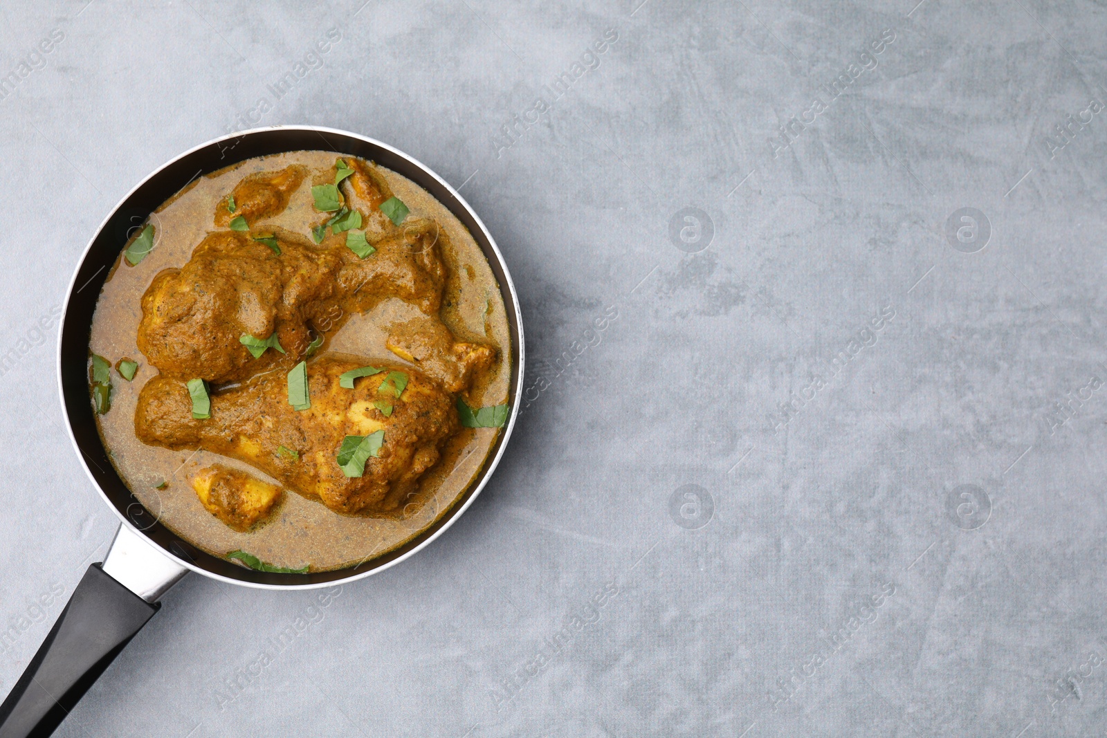 Photo of Delicious chicken with curry sauce on grey table, top view. Space for text