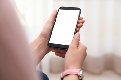 Photo of Woman holding smartphone with blank screen indoors, closeup of hands. Space for text