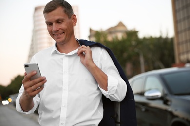 Photo of Businessman with modern smartphone on city street