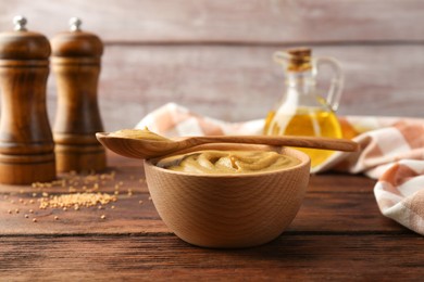 Photo of Bowl and spoon with tasty mustard sauce on wooden table