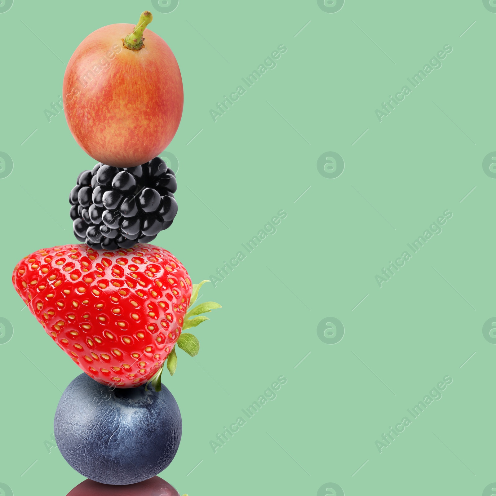 Image of Stack of different fresh tasty berries on pale aquamarine background, space for text