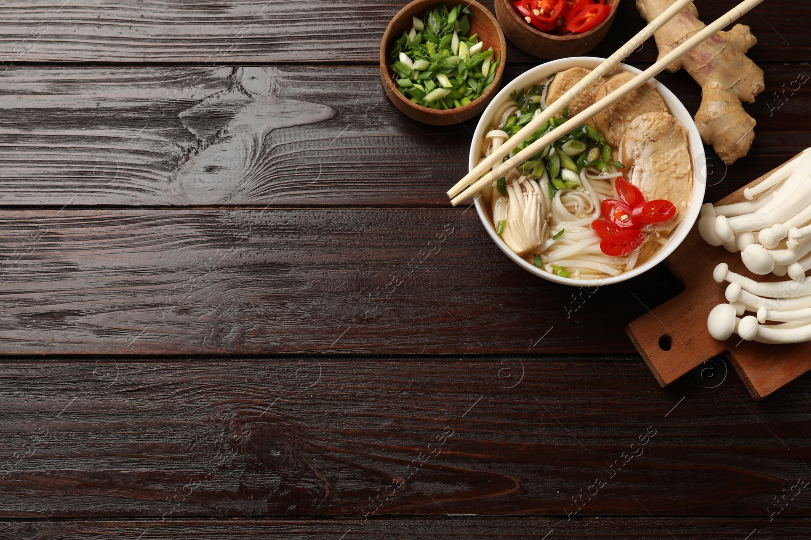 Photo of Delicious ramen with meat and ingredients on wooden table, flat lay. Space for text