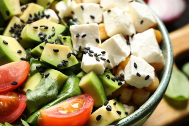Photo of Delicious avocado salad with feta cheese in bowl, closeup