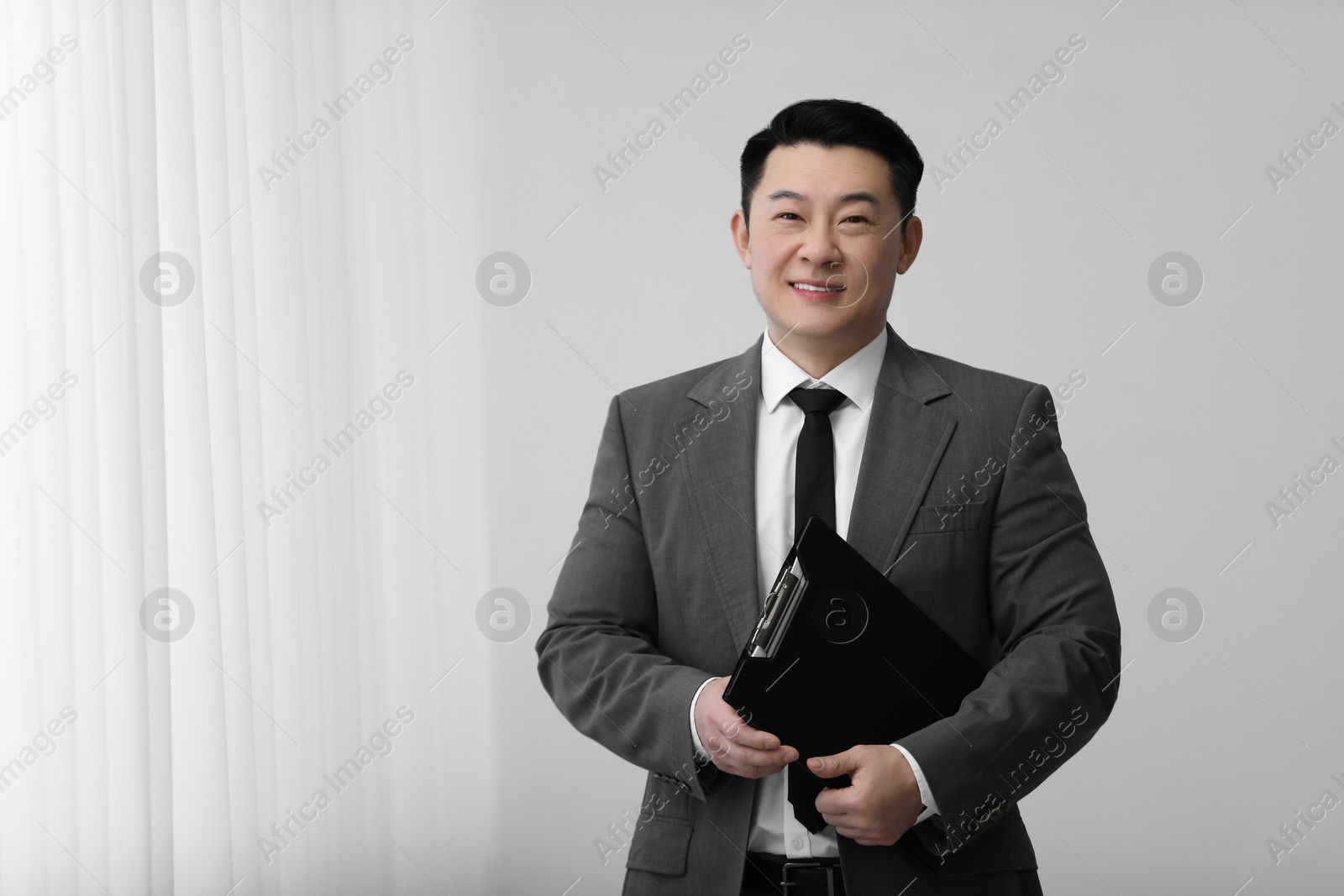 Photo of Portrait of happy notary with clipboard indoors, space for text