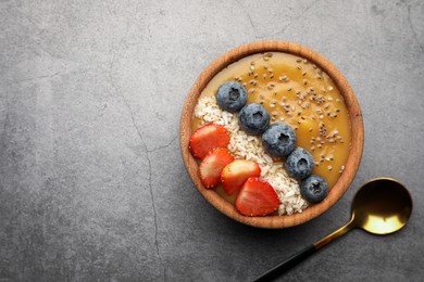 Photo of Delicious smoothie bowl with fresh berries, chia seeds and coconut flakes on grey table, flat lay. Space for text