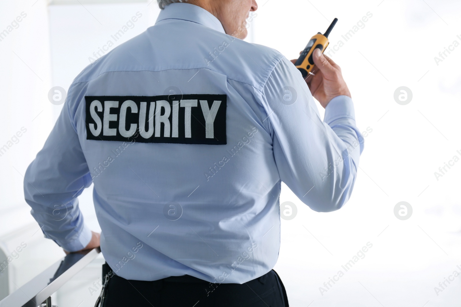 Photo of Professional security guard with portable radio set indoors, closeup