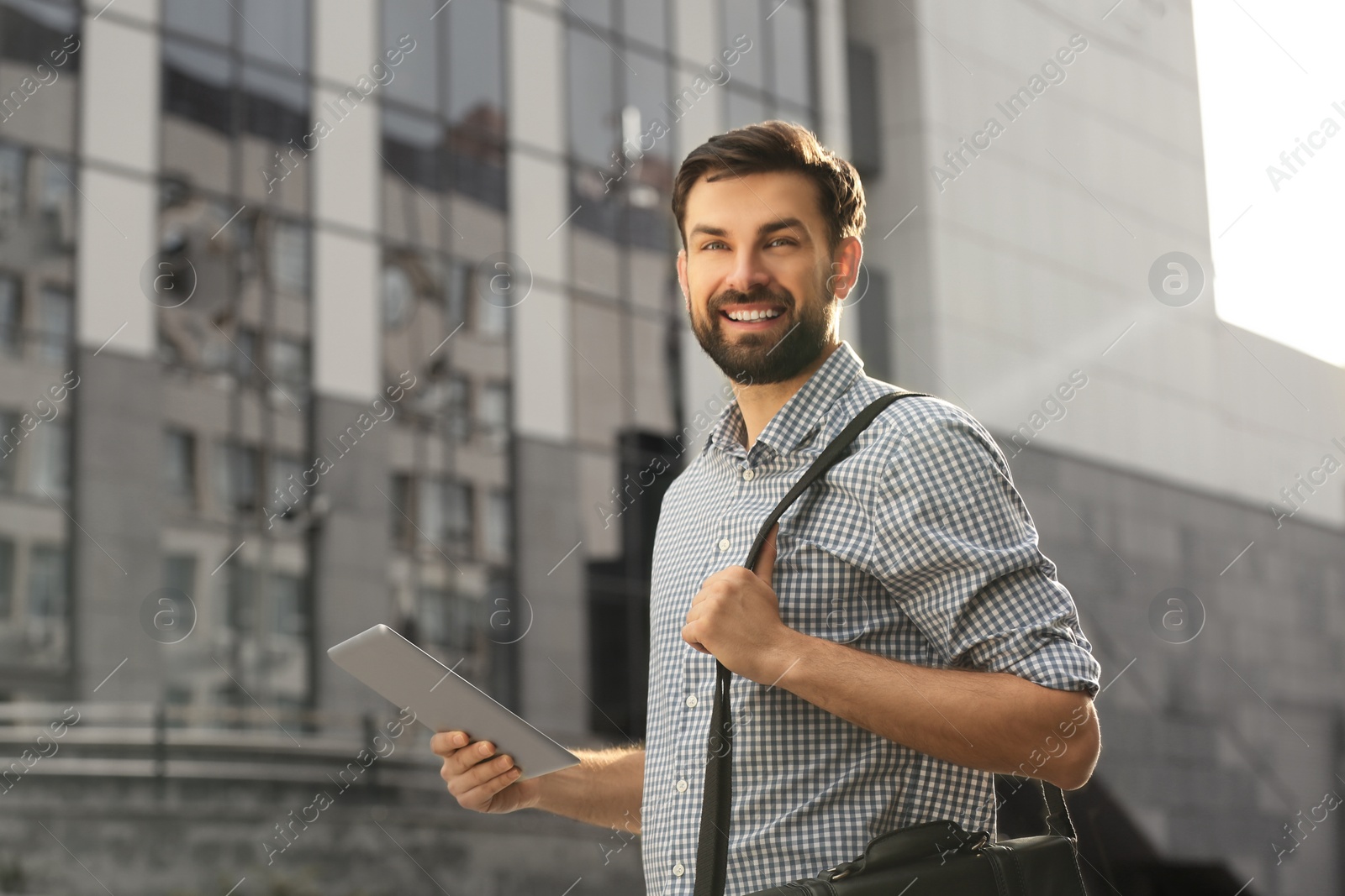 Photo of Handsome man working with tablet on city street