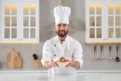 Photo of Happy chef presenting delicious dish in kitchen