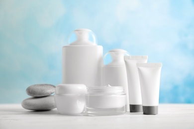 Photo of Cosmetic products on table against color background
