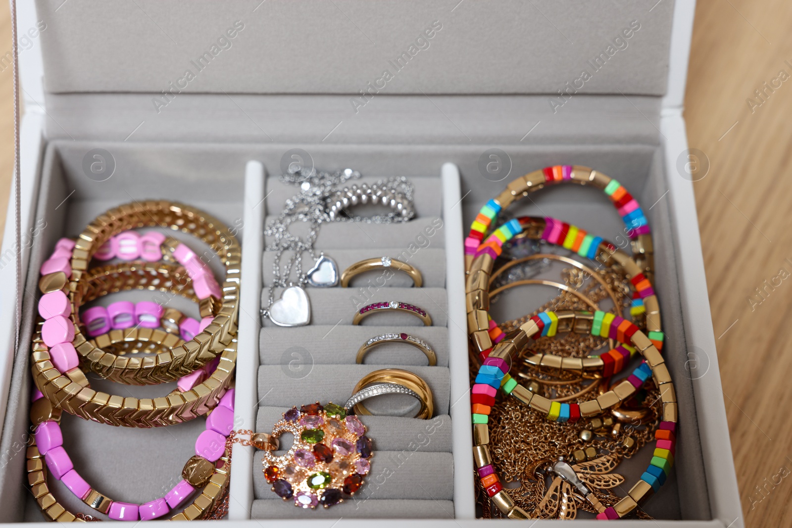 Photo of Jewelry box with stylish bracelets and other accessories on wooden table, closeup