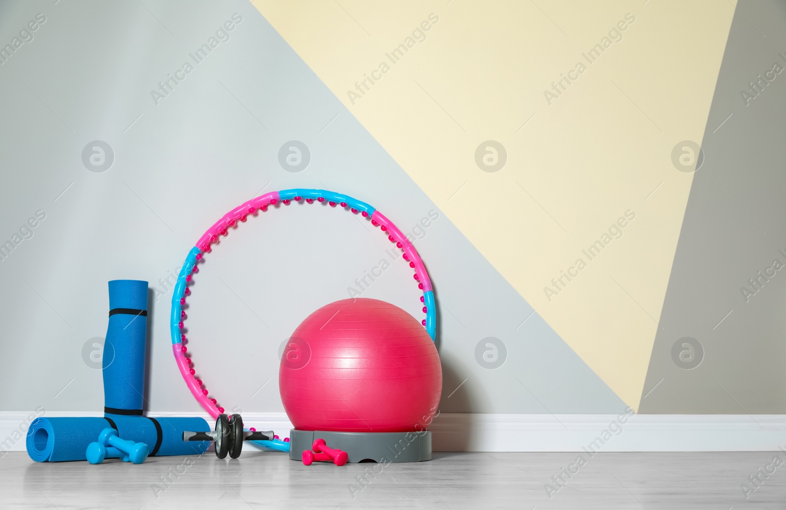 Photo of Different sports equipment near color wall in gym. Space for text