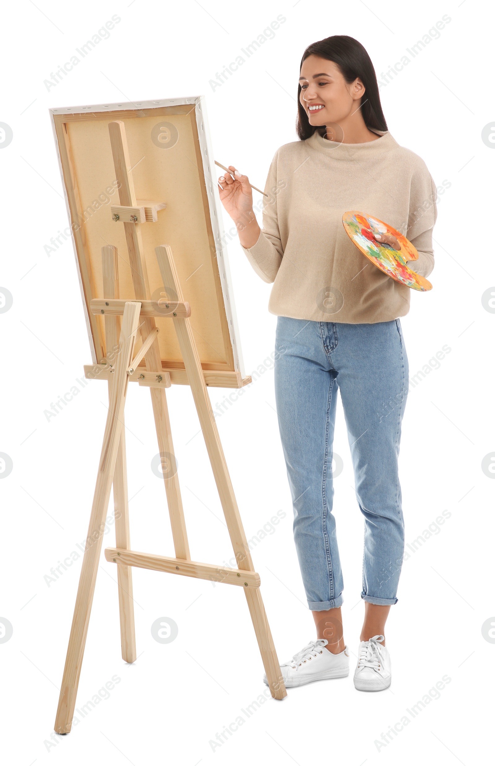 Photo of Young woman drawing on easel against white background