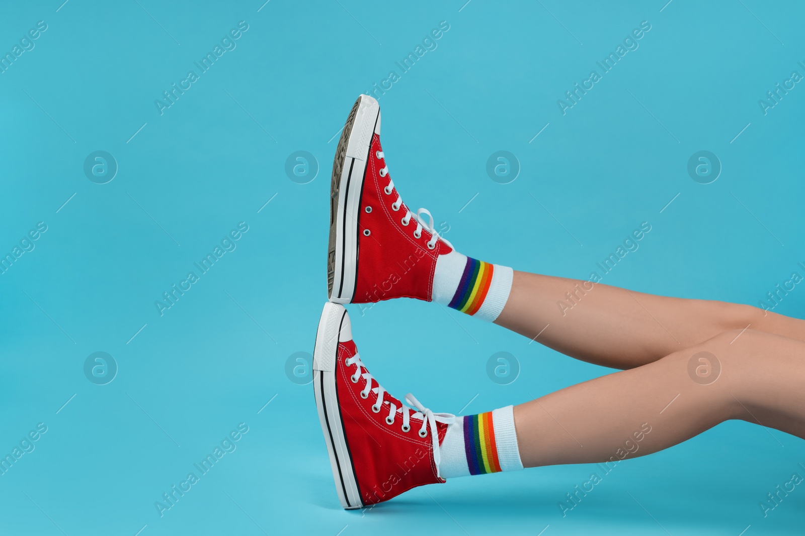 Photo of Woman in stylish gumshoes on light blue background, closeup. Space for text