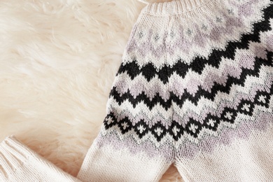 Photo of Warm knitted sweater on fuzzy carpet, top view