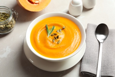 Photo of Bowl with tasty pumpkin soup served on gray table