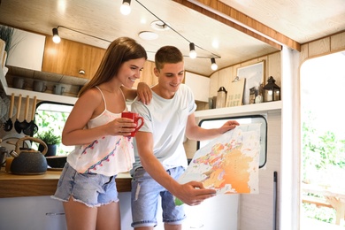 Photo of Young travelers with world map planning trip in motorhome