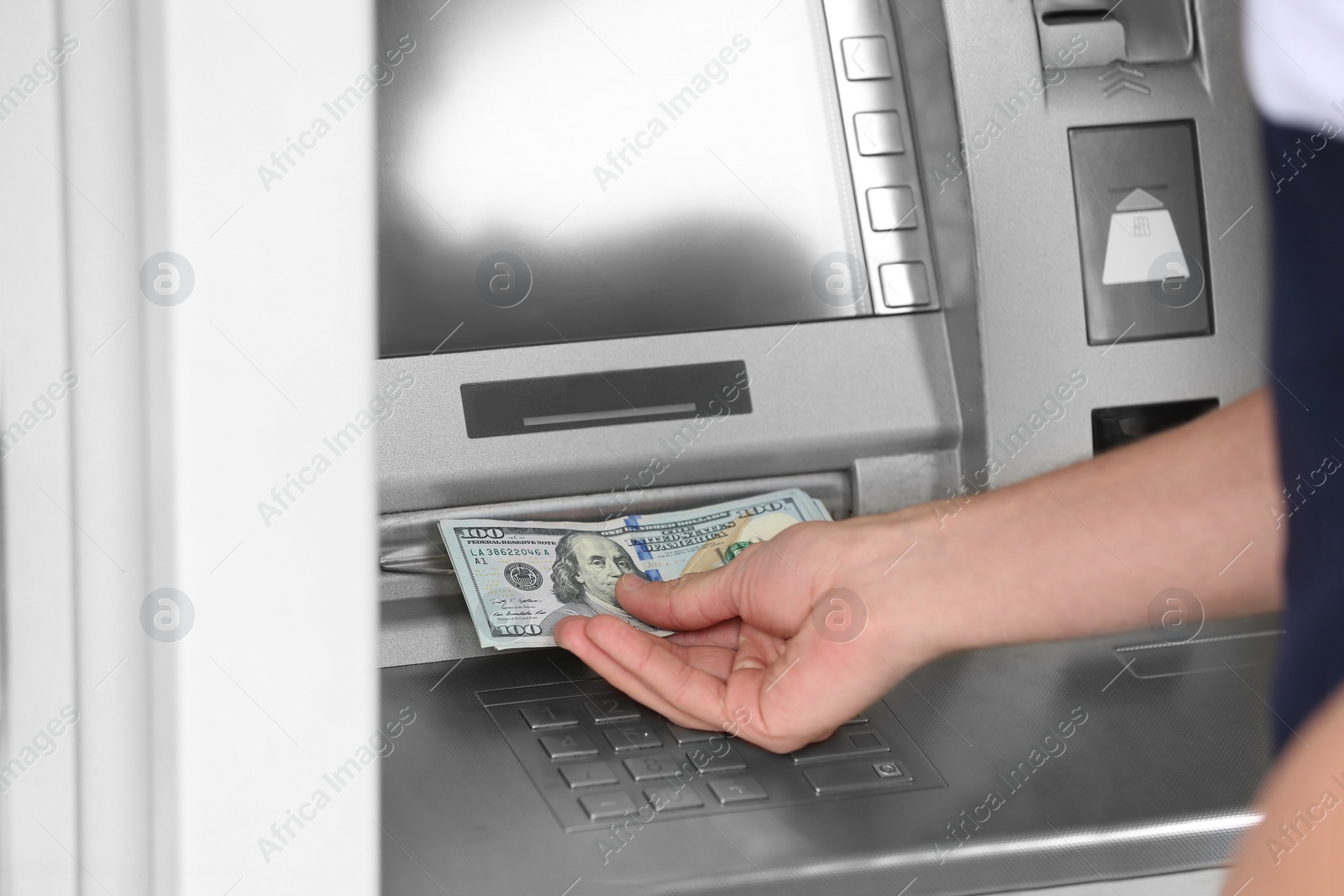 Photo of Man taking money from cash machine outdoors, closeup