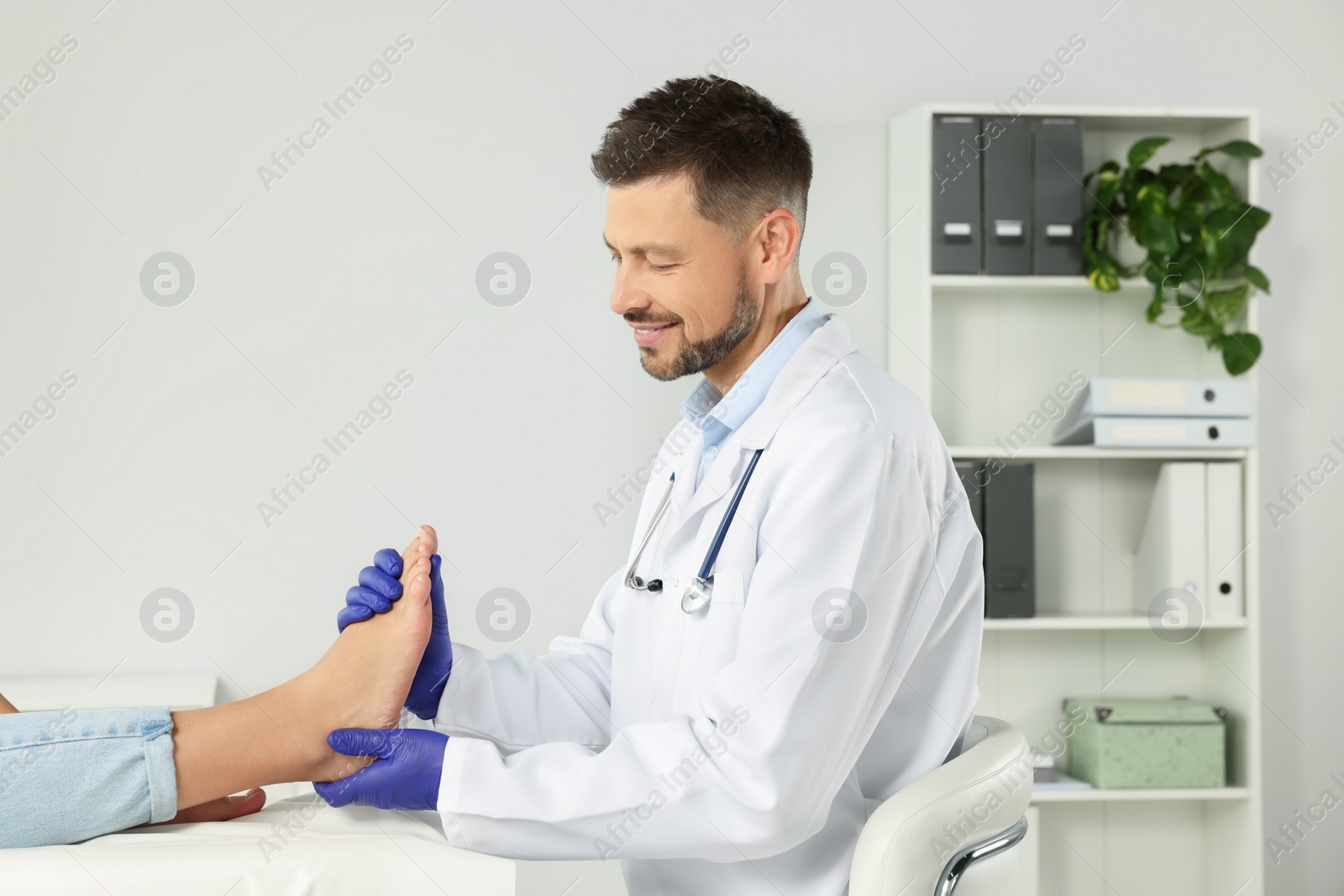 Photo of Male orthopedist examining patient's foot in hospital