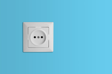 Image of Light blue wall with power socket, space for text. Electrical supply